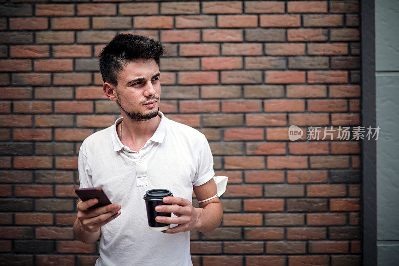 Take A Way Coffee, Man Drinking Coffee And Looking At Phone in Front Of The Stone Wall .在石墙前喝咖啡和看手机